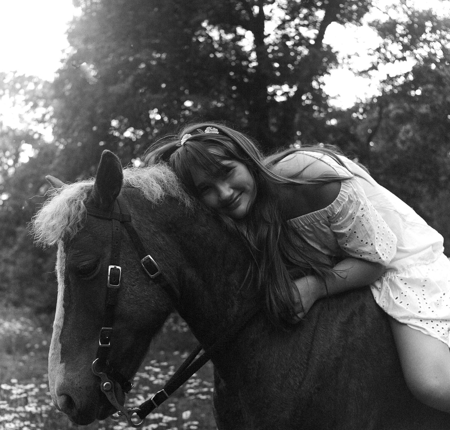 Black and white photos of a bride gently petting and bonding with a dark horse in a natural outdoor setting.