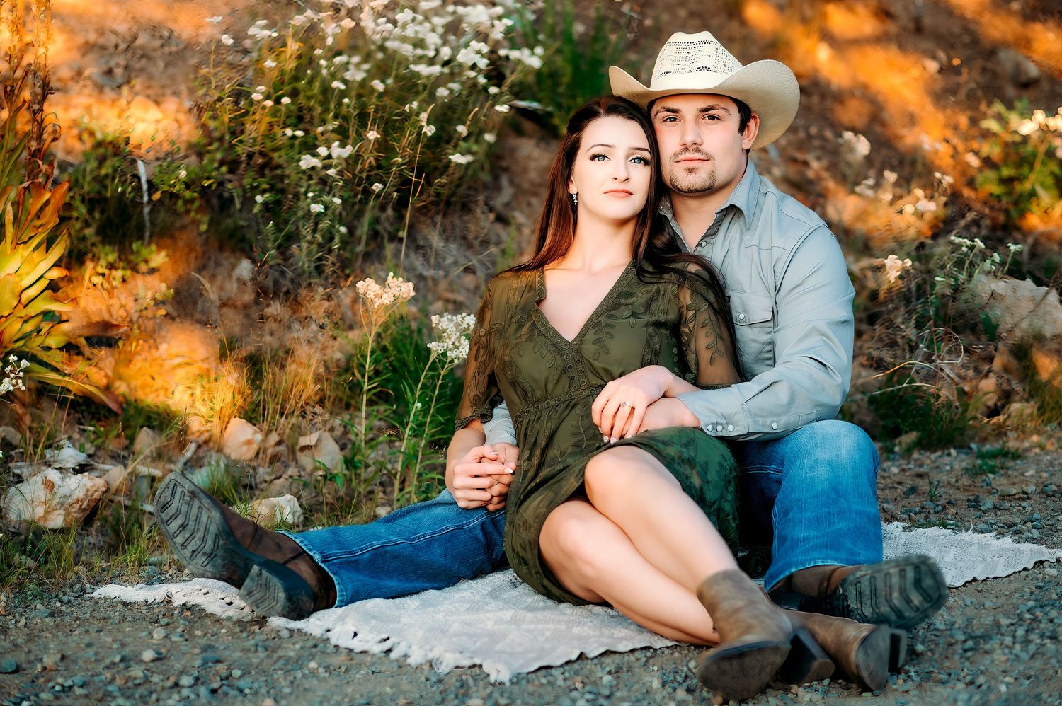 Couple sitting together on rocks during golden hour sunset in natural outdoor setting.