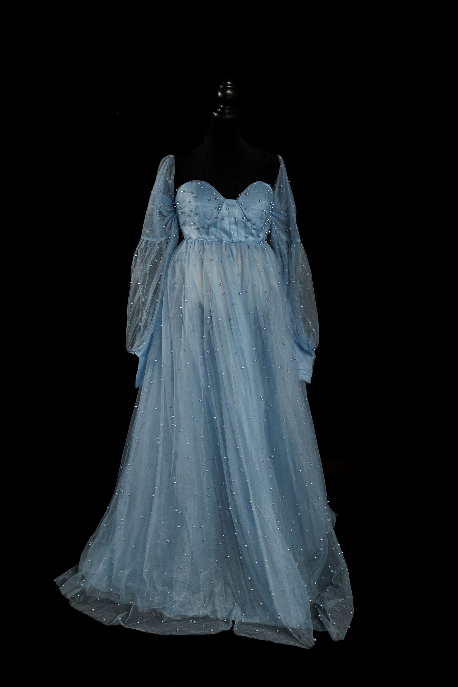 Emerald green sheer tulle robe with dramatic ruffled sleeves displayed on a black mannequin against dark background.