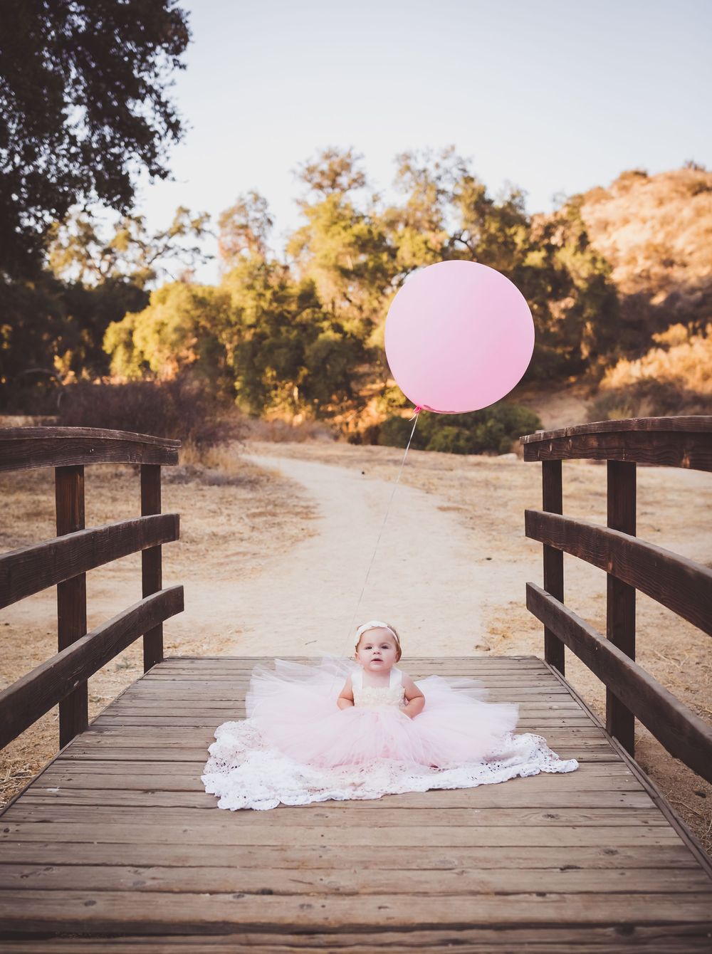 A series of photos showing a pink balloon floating across a wooden bridge walkway in a natural outdoor setting.
