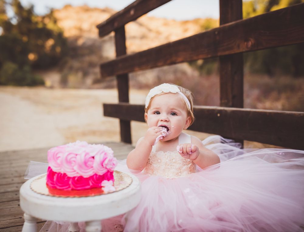 A series of cake smash photos showing a baby in a pink tutu dress enjoying their first birthday cake celebration.