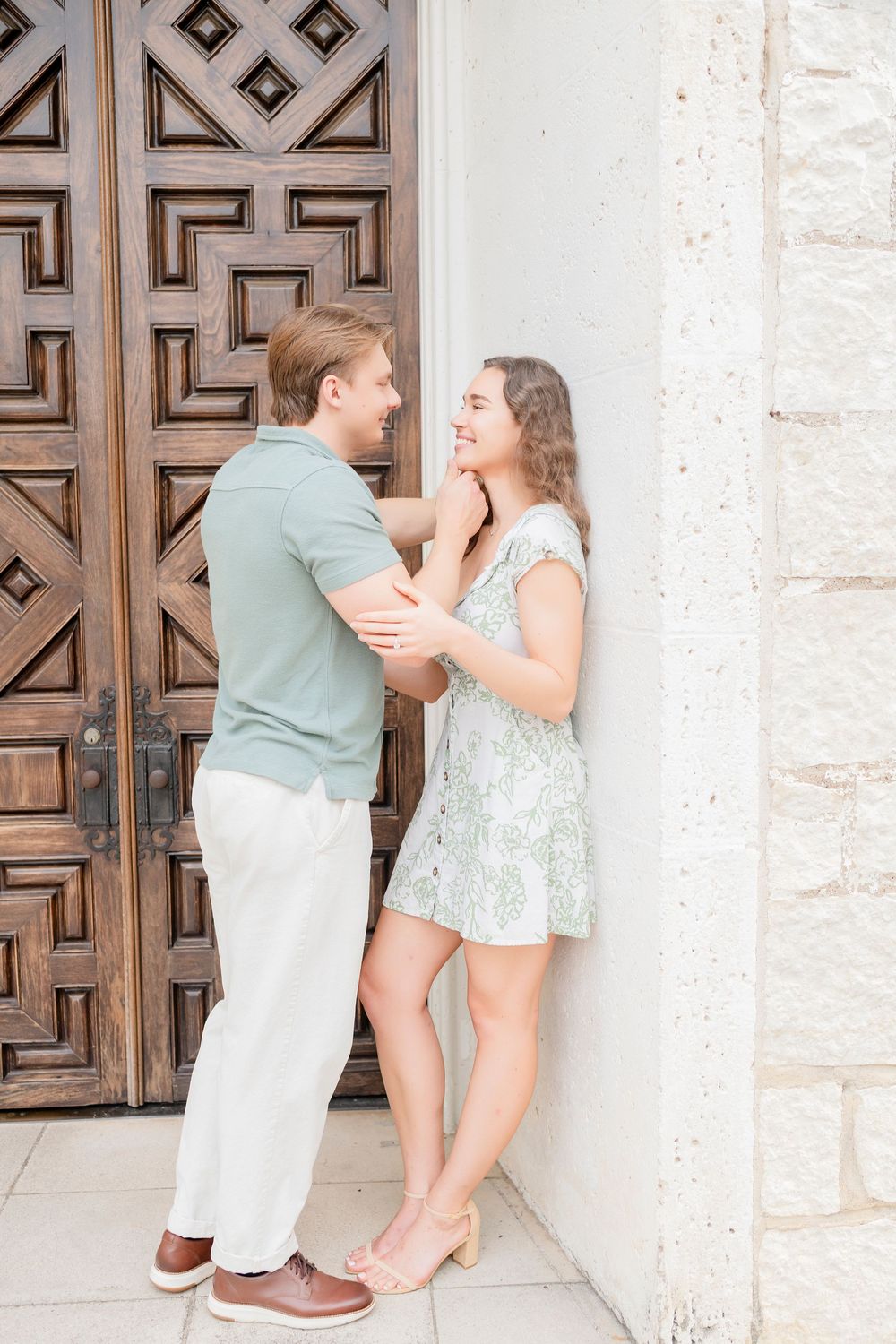 A couple shares sweet moments together against an ornate wooden door backdrop in matching mint and white outfits.