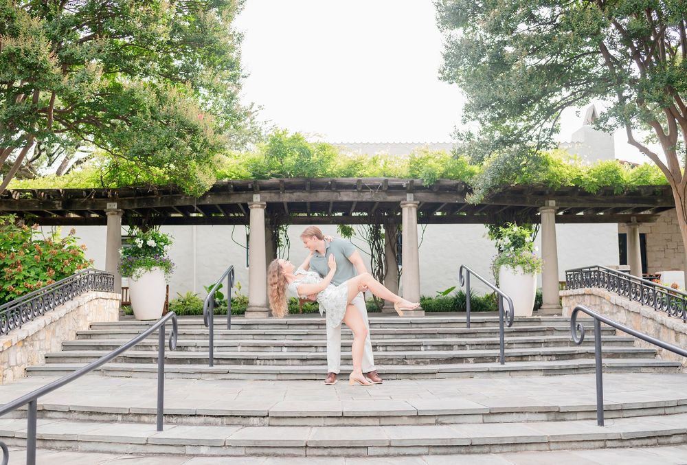 A panoramic view of concrete steps and handrails at a skate spot with trees and greenery in the background.