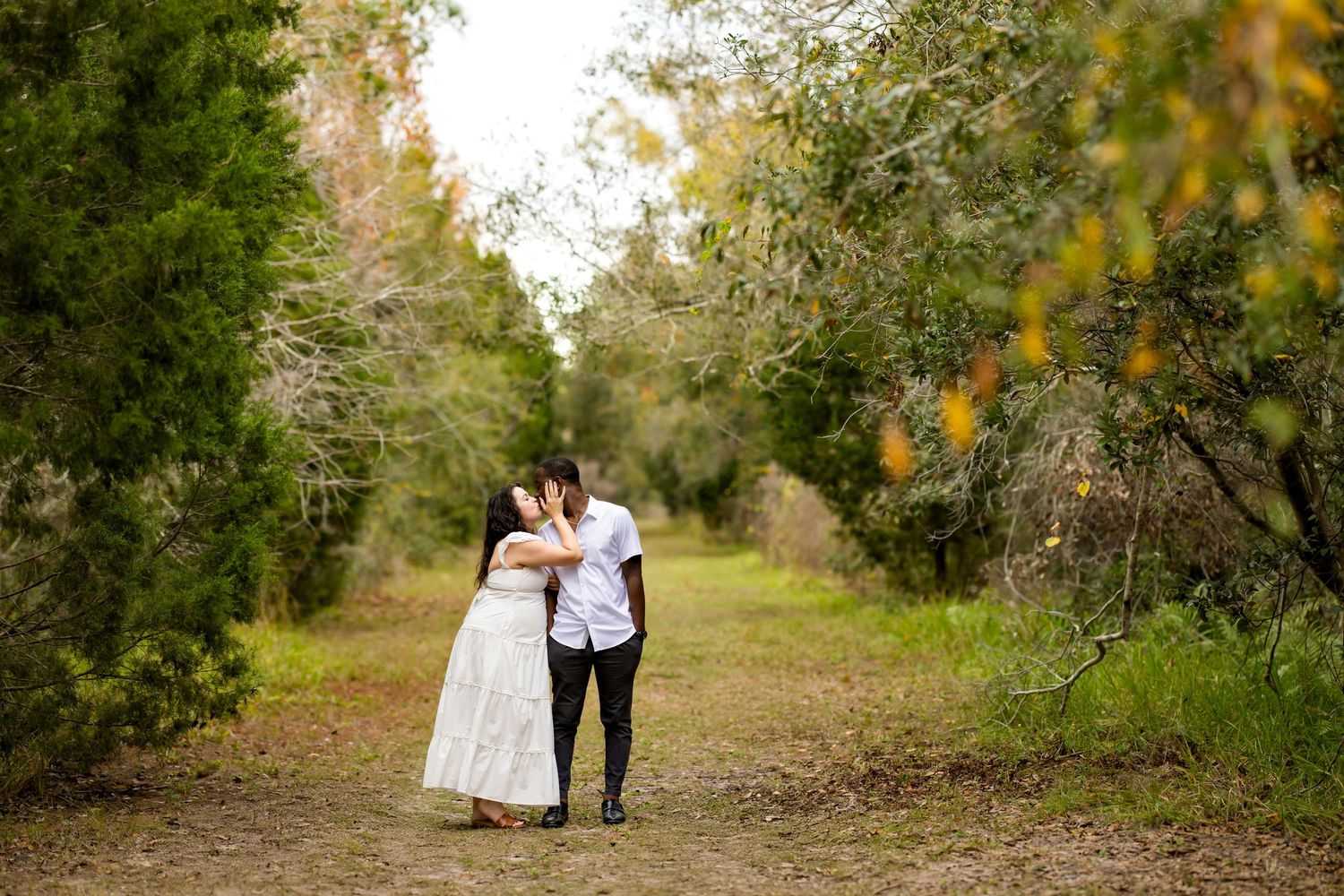 A couple walks hand in hand down a tree-lined path during a romantic autumn photo session.