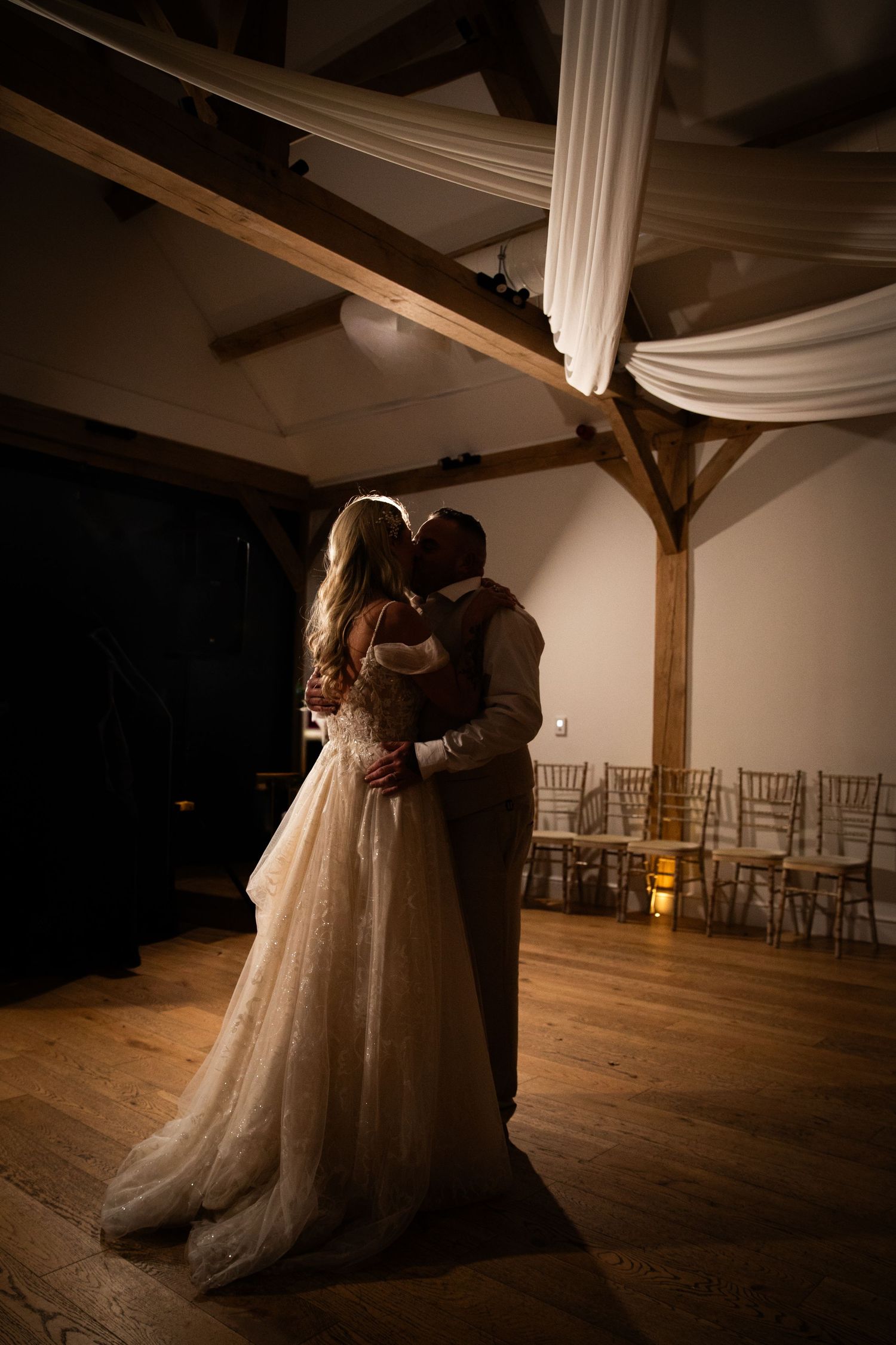 A couple dances together in a sun-drenched garden during golden hour, creating a romantic silhouette against the grass.