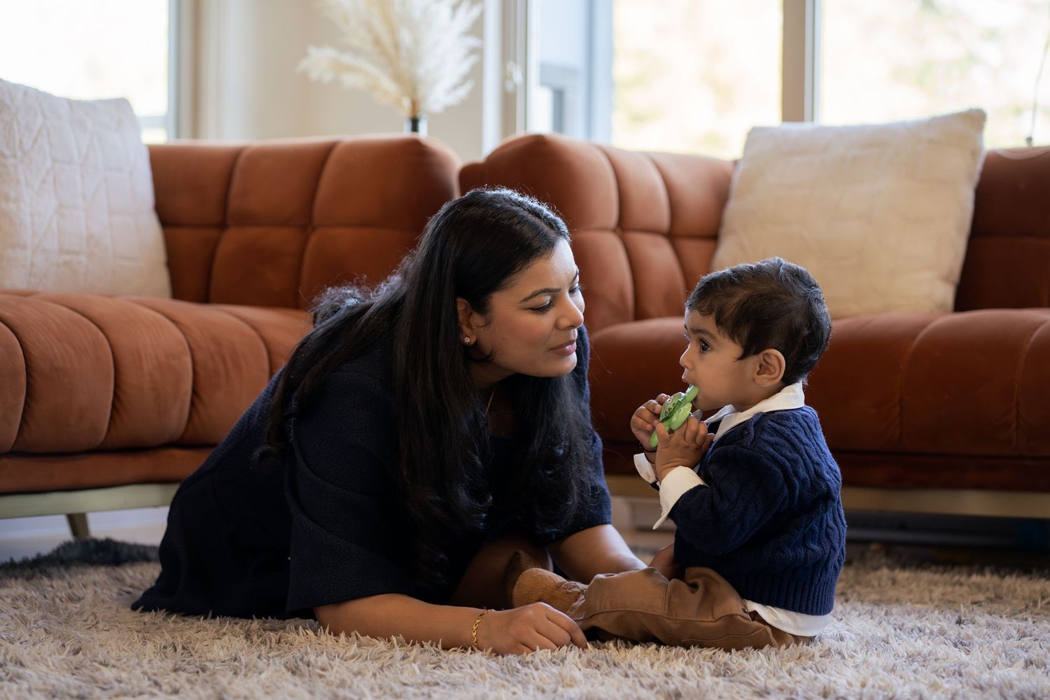 A sequence of five photos showing a tender moment between parent and child lying on a brown carpet.
