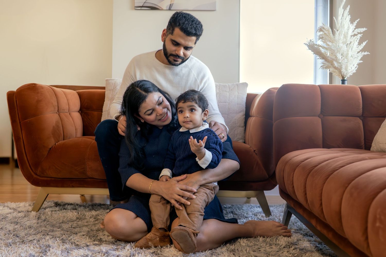 Family enjoying quality time together while sitting on a brown sectional sofa in their living room.