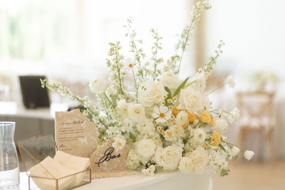 White floral arrangements with delicate blooms and greenery decorate a light-filled event space.