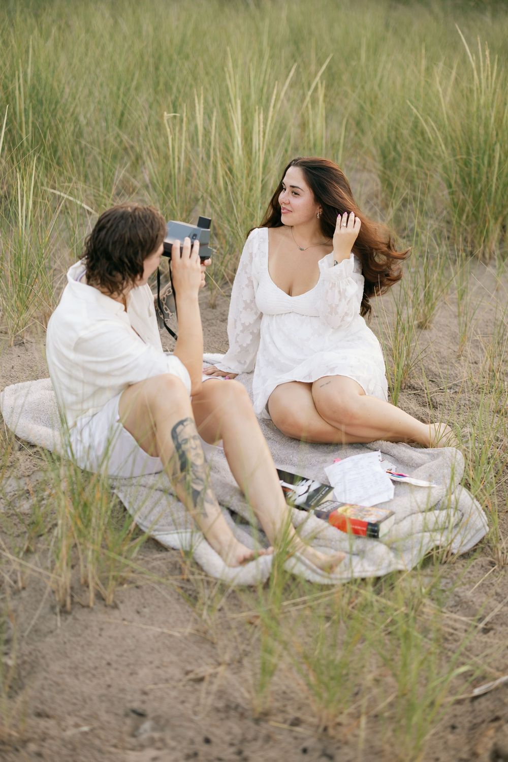 A series of photos showing someone in a white dress lounging on beach grass while taking pictures with a camera.