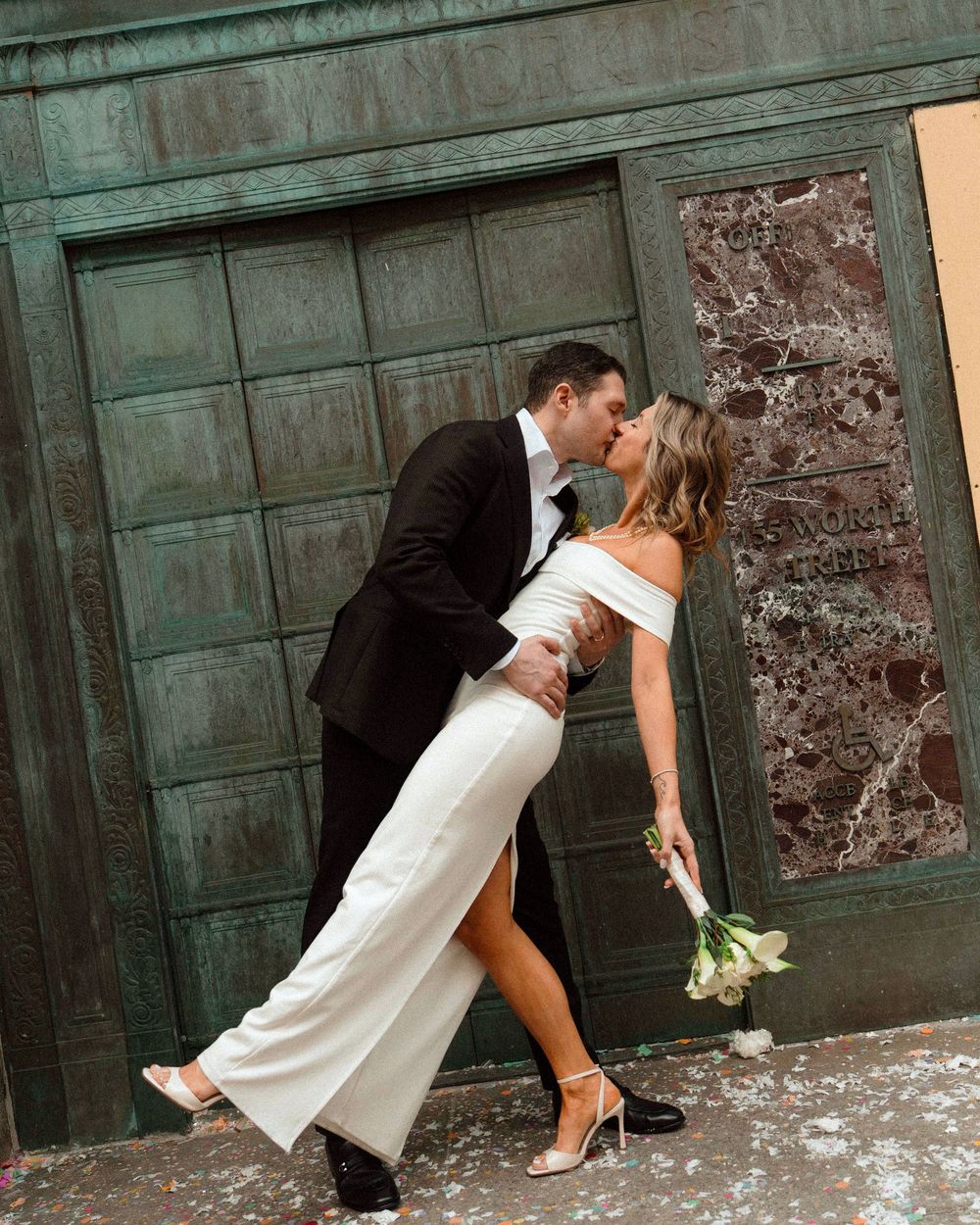 Romantic dip pose in front of vintage green door with wedding bouquet.