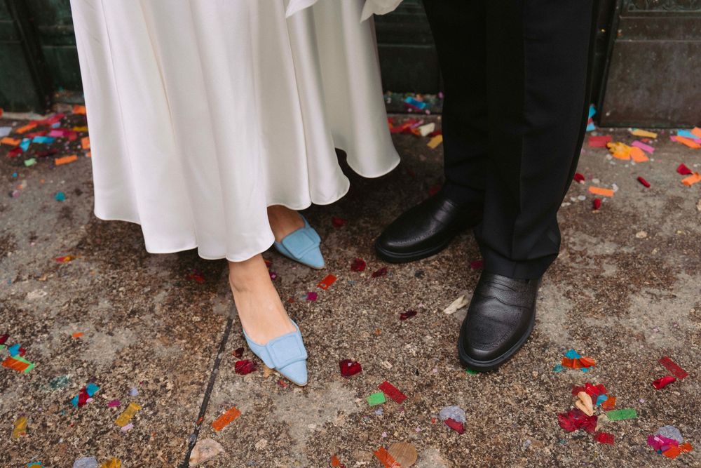 Scattered red and orange confetti on ground with formal dress and shoes visible.