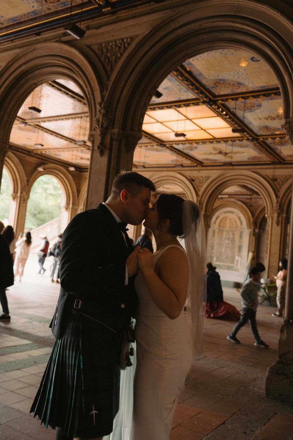 A couple dances beneath elegant stone arches in a historic passageway.