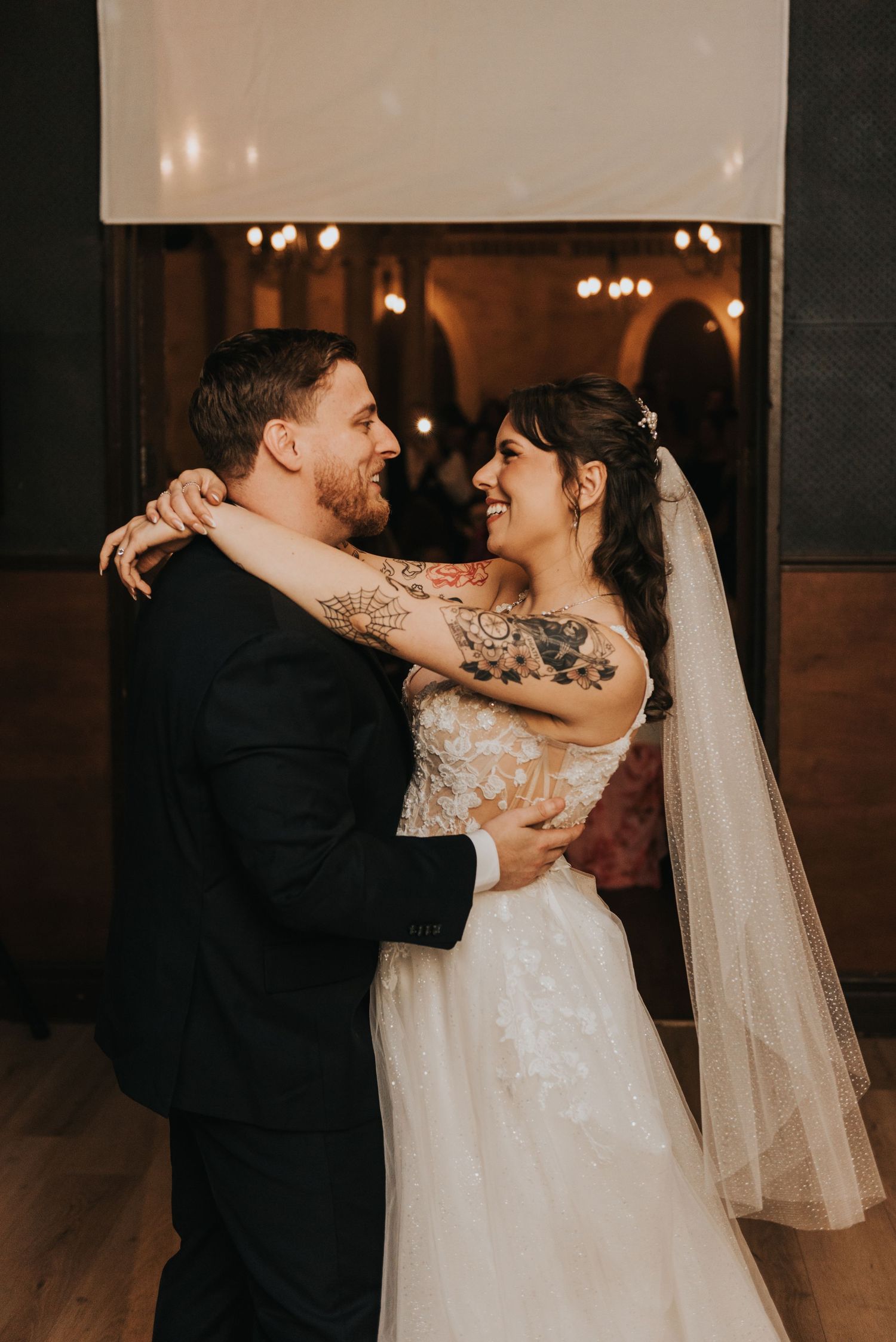 Newlyweds share intimate dance moments in a dimly lit reception venue with romantic lighting.