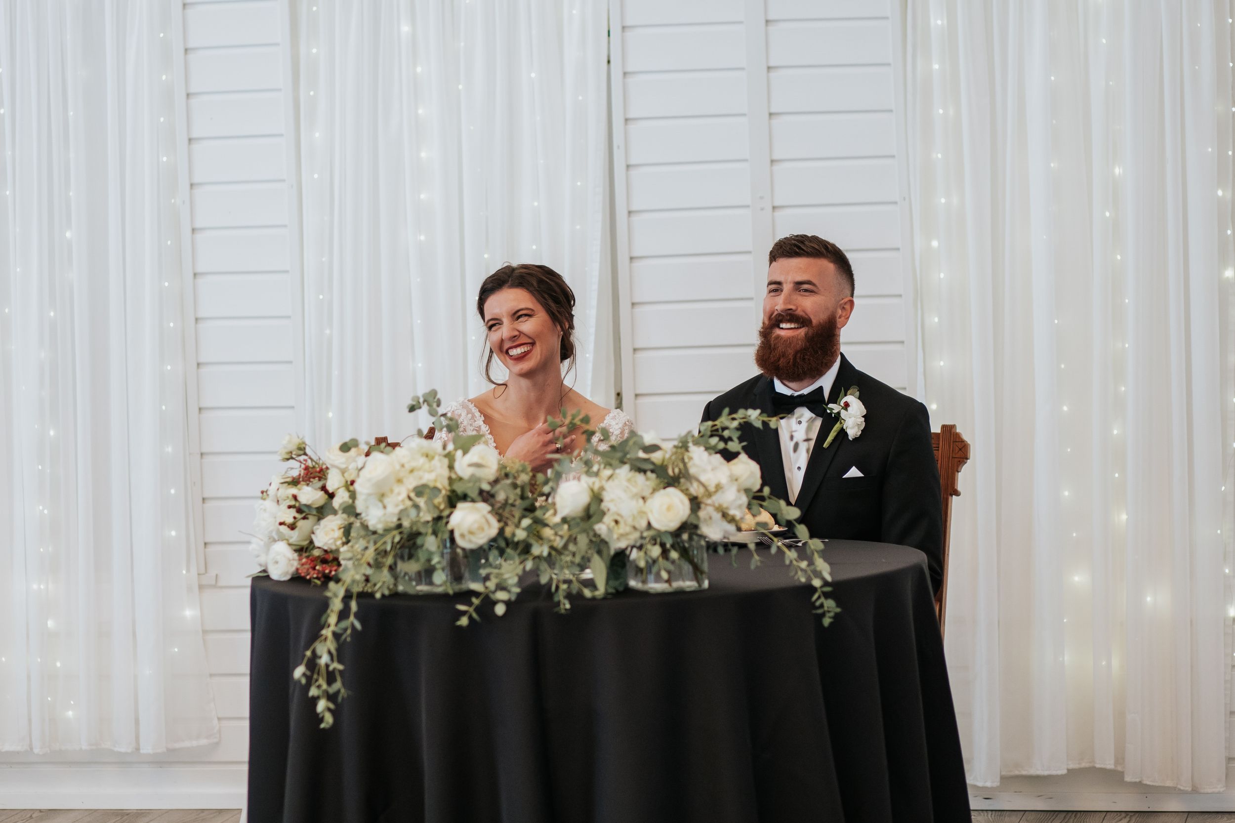 A bright white chapel interior decorated with floral arrangements for a wedding celebration.