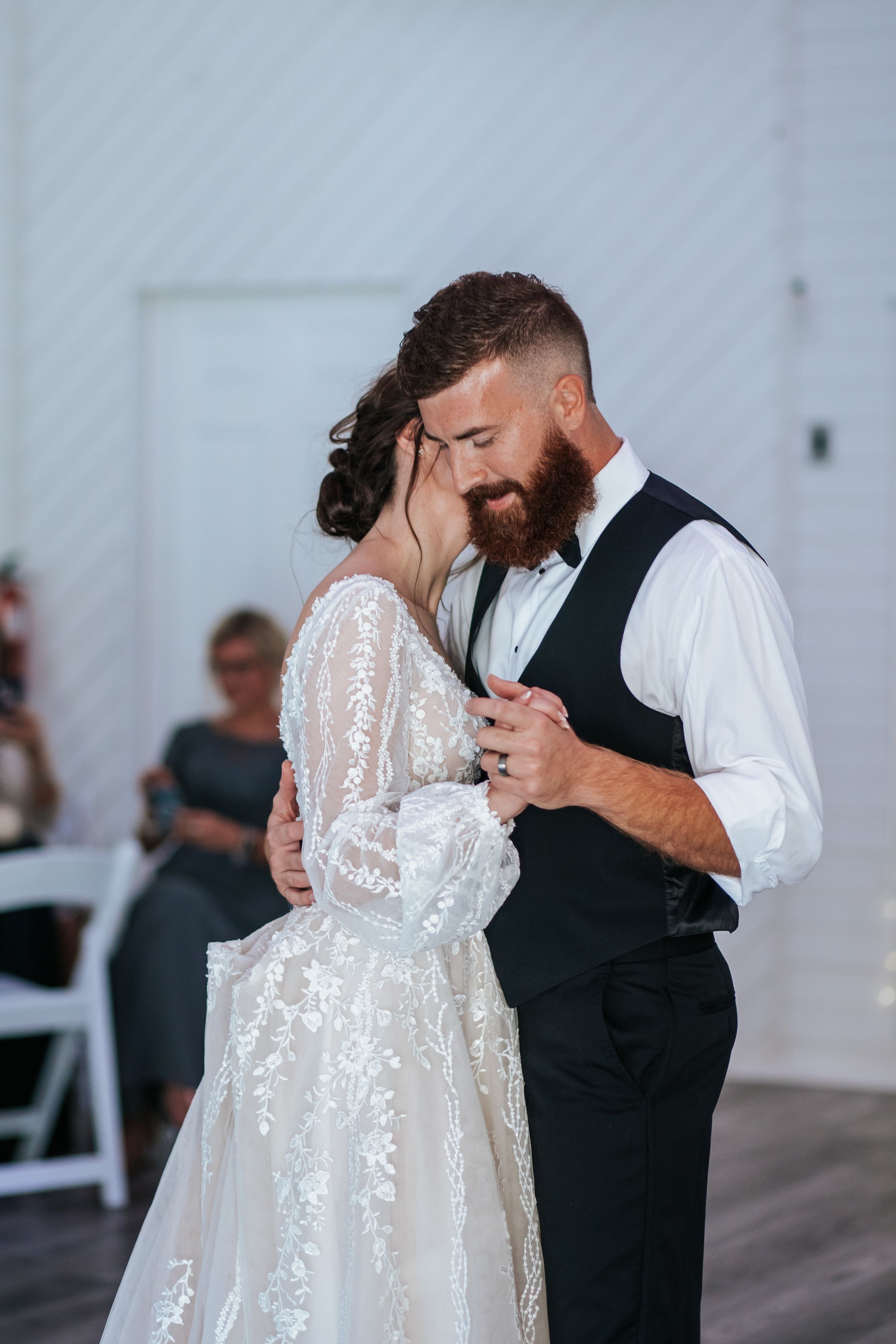 Couple sharing an intimate dance in a white reception venue with elegant decor.