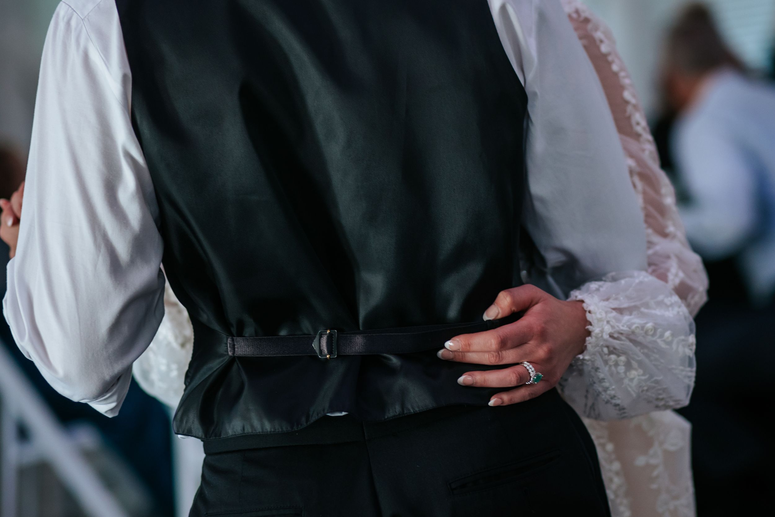 Close-up view of wedding couple's dance showing detailed lace sleeves of bridal gown.