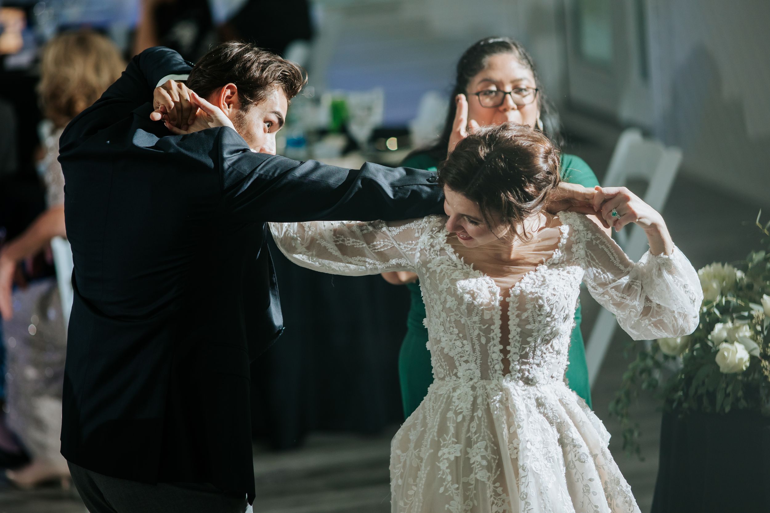 Wedding couple dancing while guests watch in a brightly lit reception venue.