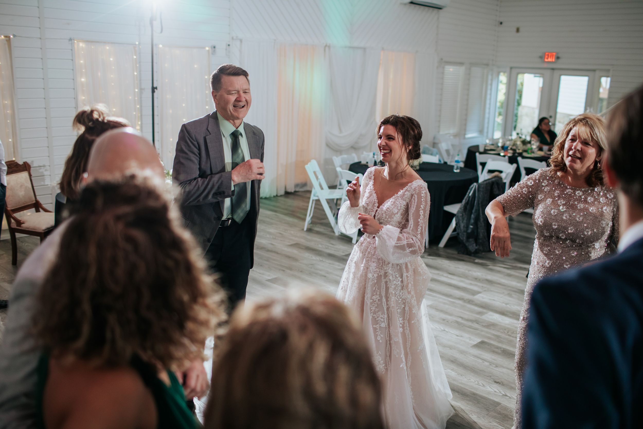 Wedding reception venue with guests seated at tables and string lights creating ambiance.