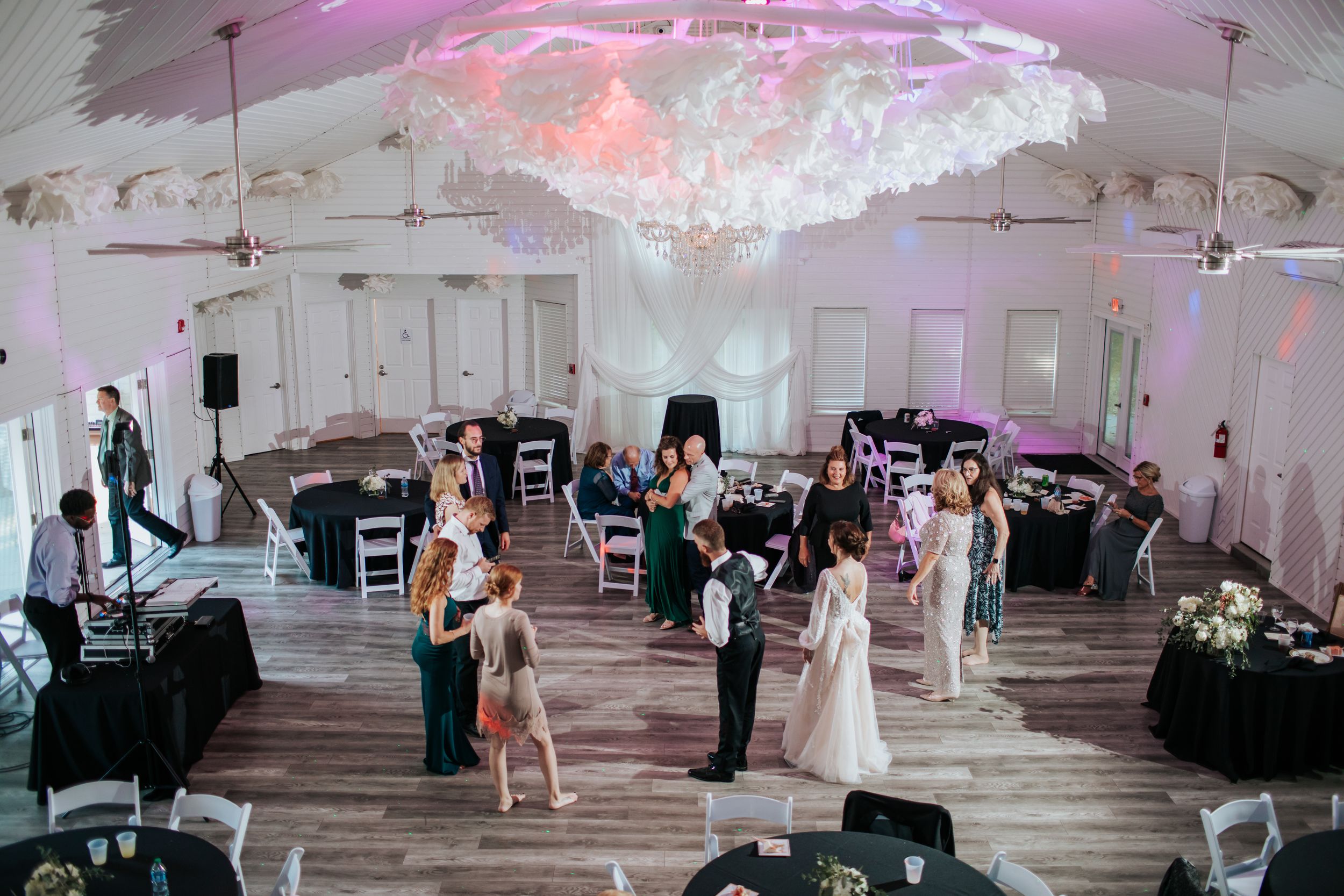 Large reception hall decorated with pink lighting and elegant white decor.