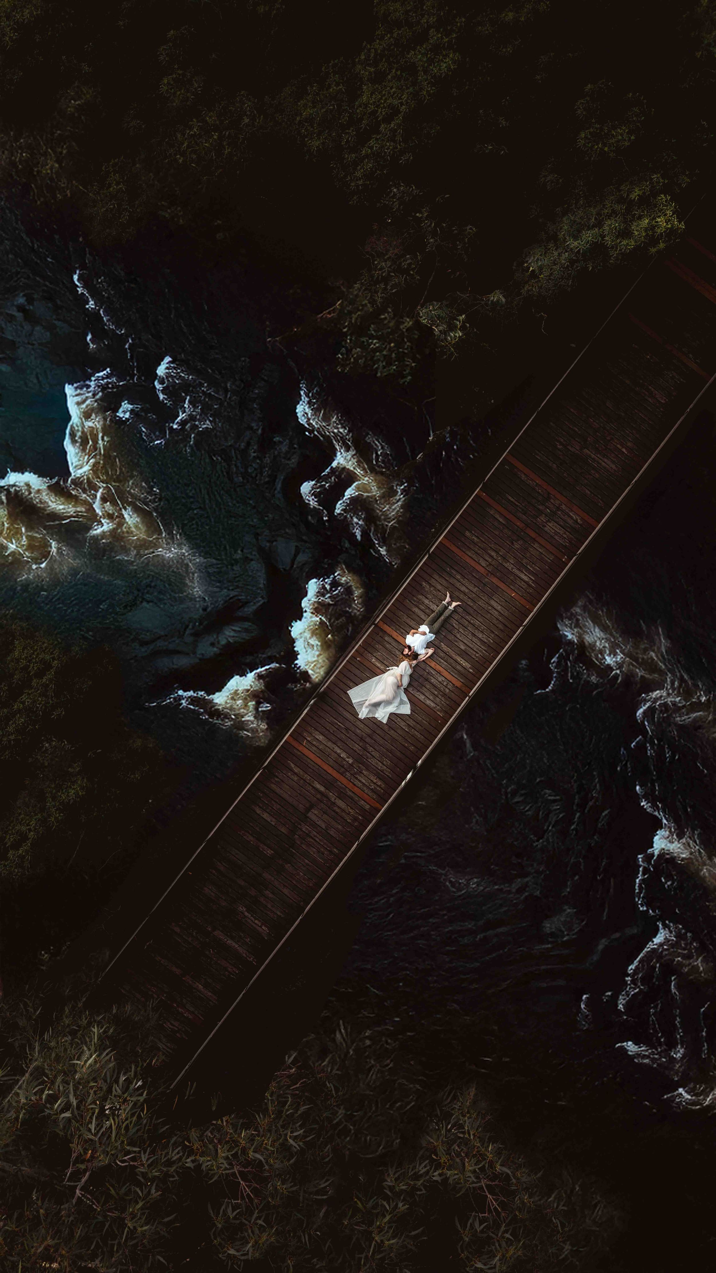 Aerial Maternity Photo- Murrays Beach Jervis bay. Couple laying on bridge with river flowing underneath