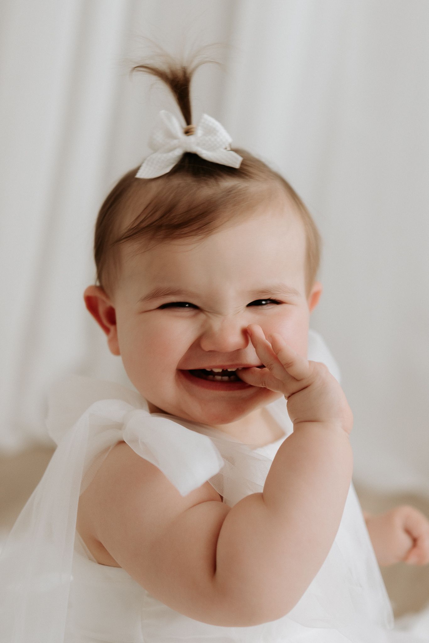 Sleeping newborn baby in a cream knit romper with button detail, curled up peacefully.