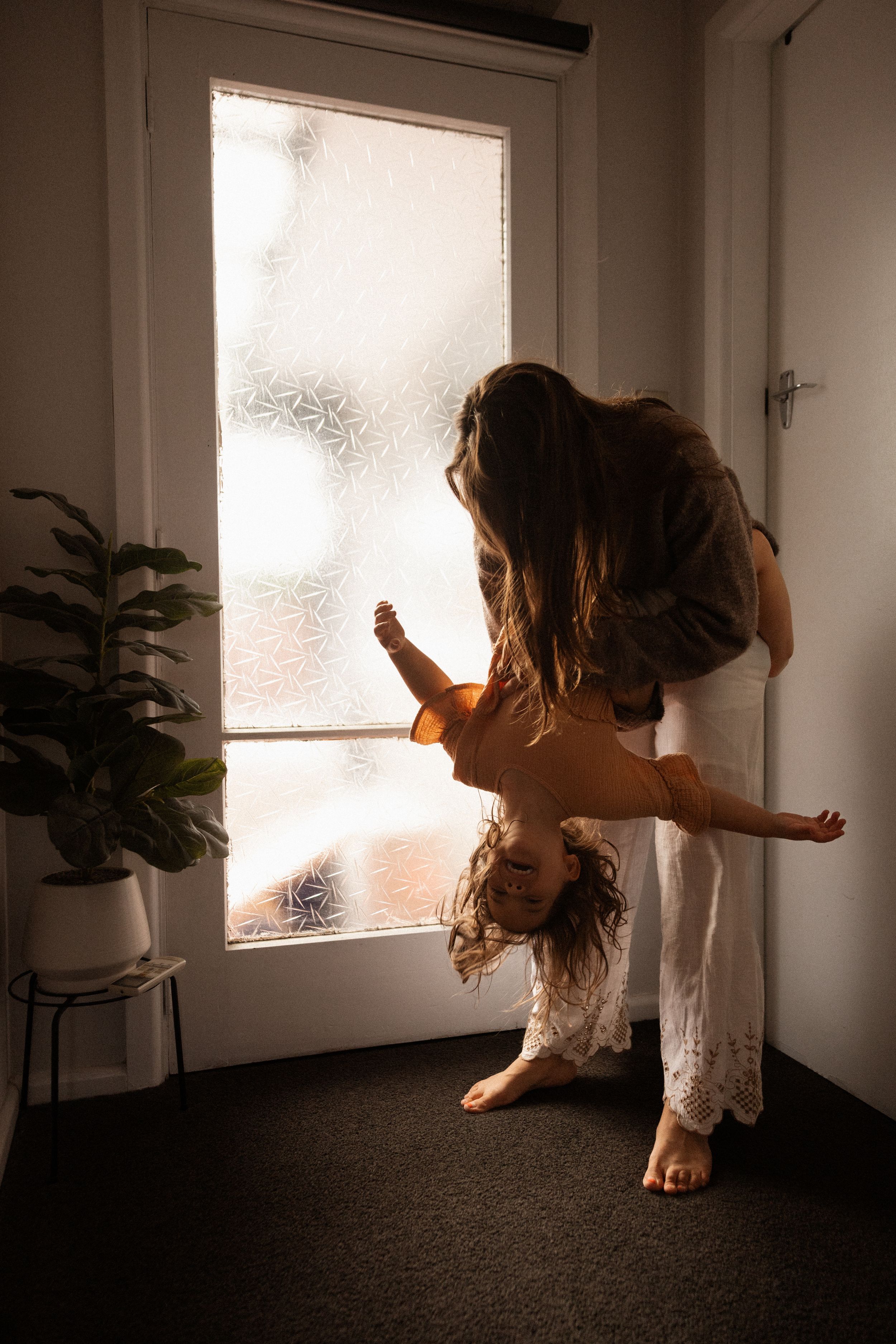 mum playing with her daughter holding her upside down at home
