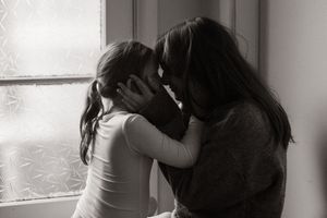 mum and daughter holding each other's faces at home