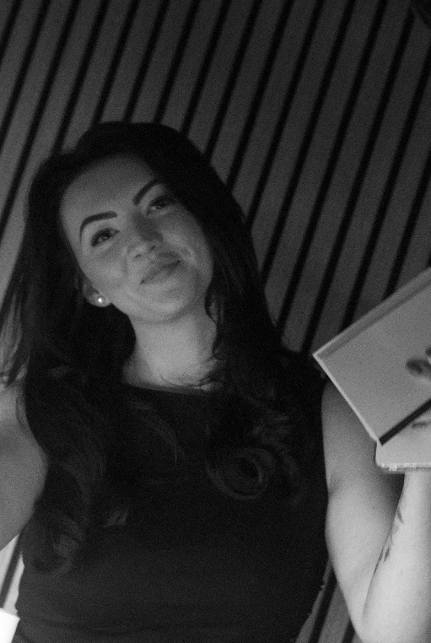 Black and white portrait of a woman with long dark hair holding a tablet, smiling softly.