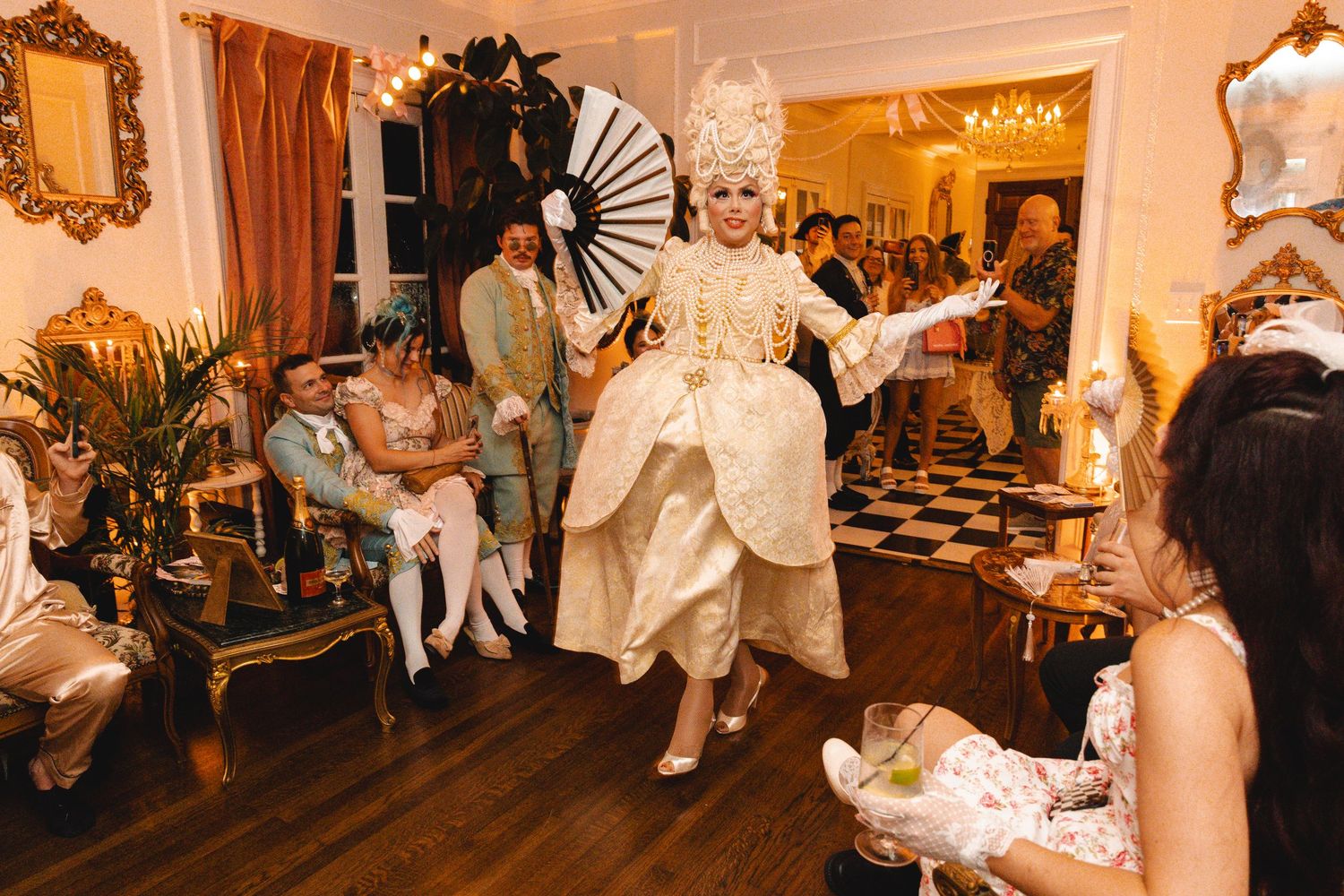 Performer in elaborate gold baroque gown and white powdered wig dancing at a Marie Antoinette themed event.