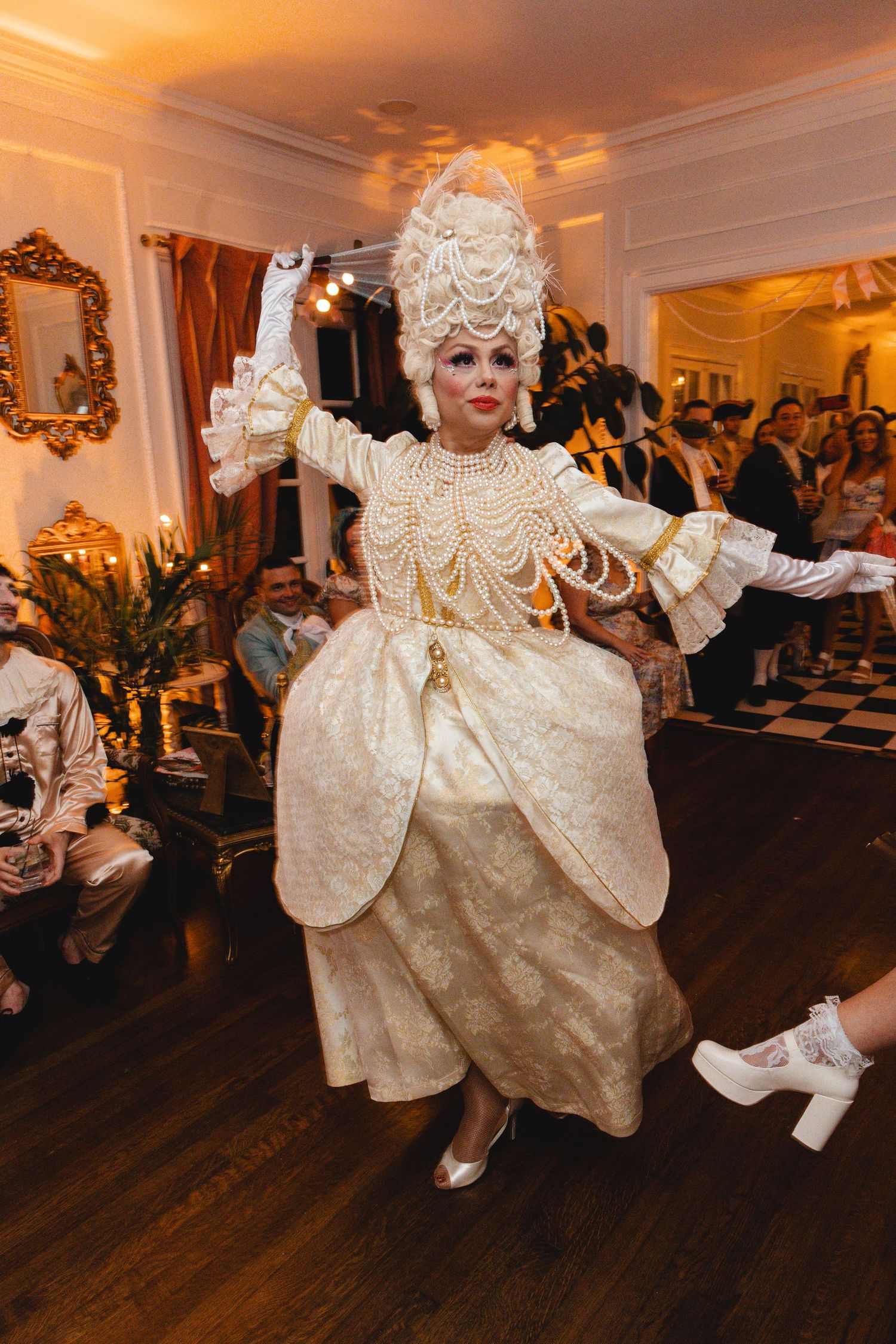 Performer in ornate ivory Marie Antoinette costume with pearl headpiece dancing at luxury event.