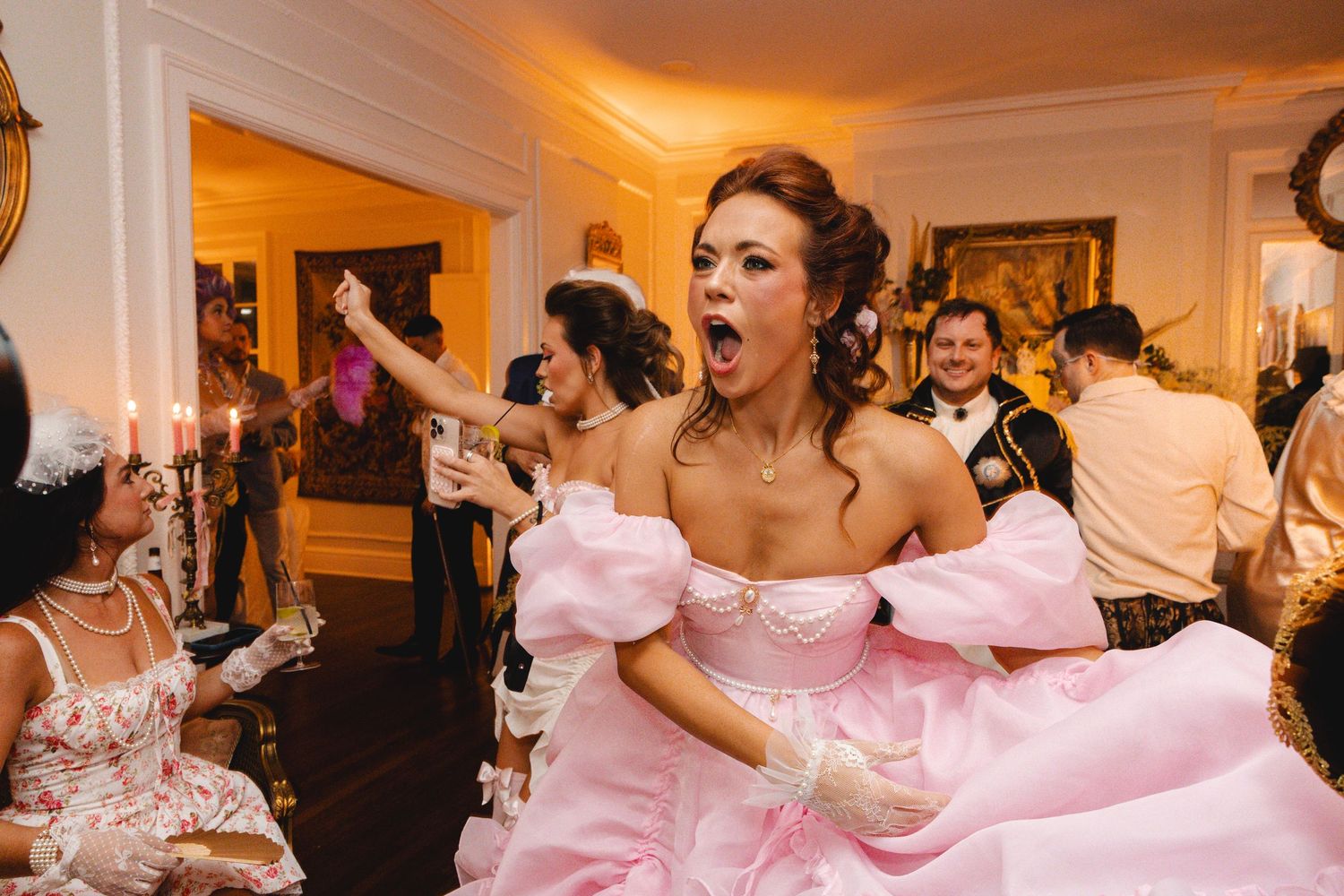 Woman in pink ball gown with open mouth expression dancing at elegant costume party.