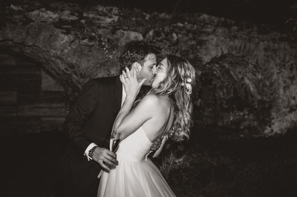 Artistic black and white wedding portrait against textured stone wall background.