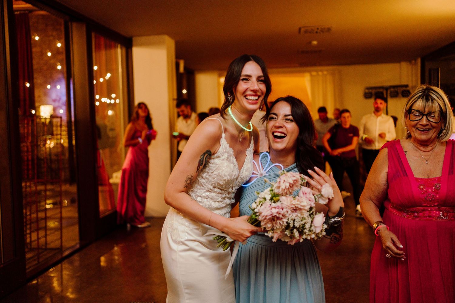 Radiant bride poses with bridesmaid holding bridal bouquet after the bouquet toss at wedding reception.