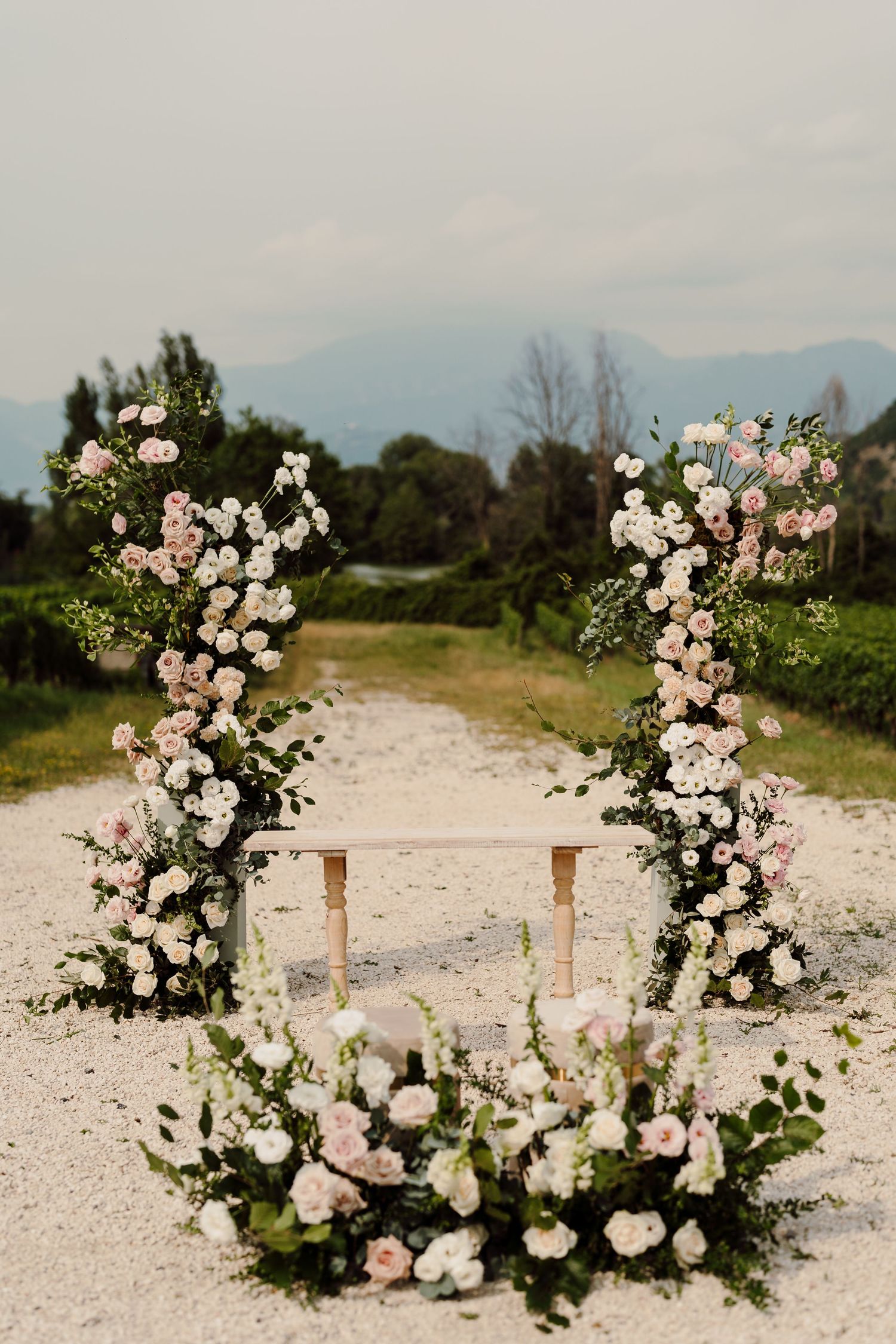 Beautiful wedding altar with two floral columns of pink and white roses and mountain views behind.