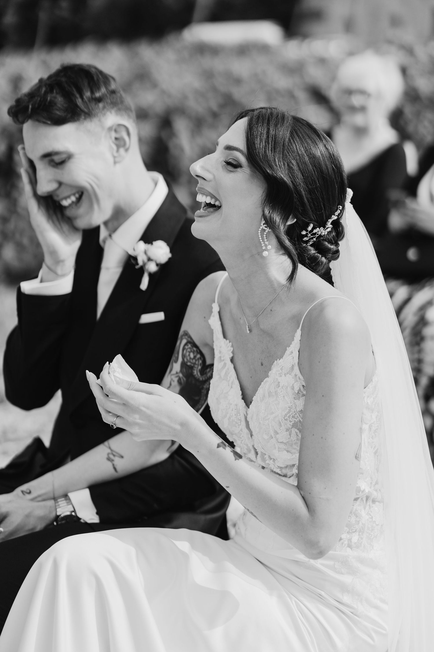 Black and white photo of bride and groom laughing together during wedding ceremony.