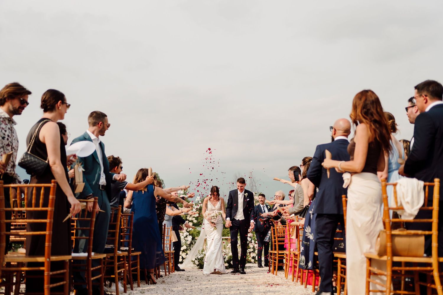Bride and groom recessional walk as guests celebrate at scenic outdoor wedding.