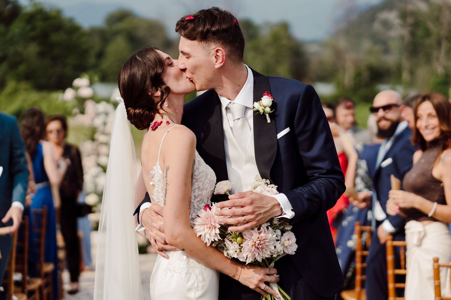 Newlyweds share first kiss as married couple during outdoor wedding ceremony.