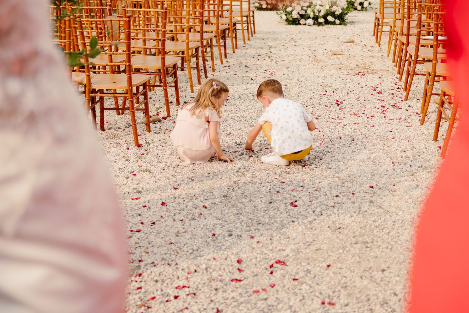 Two young children playing with flower petals on wedding ceremony aisle.