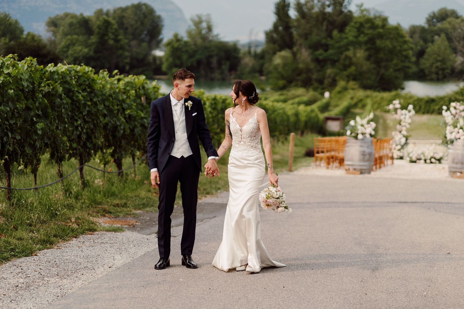 Bride and groom walking hand in hand through vineyard on wedding day.