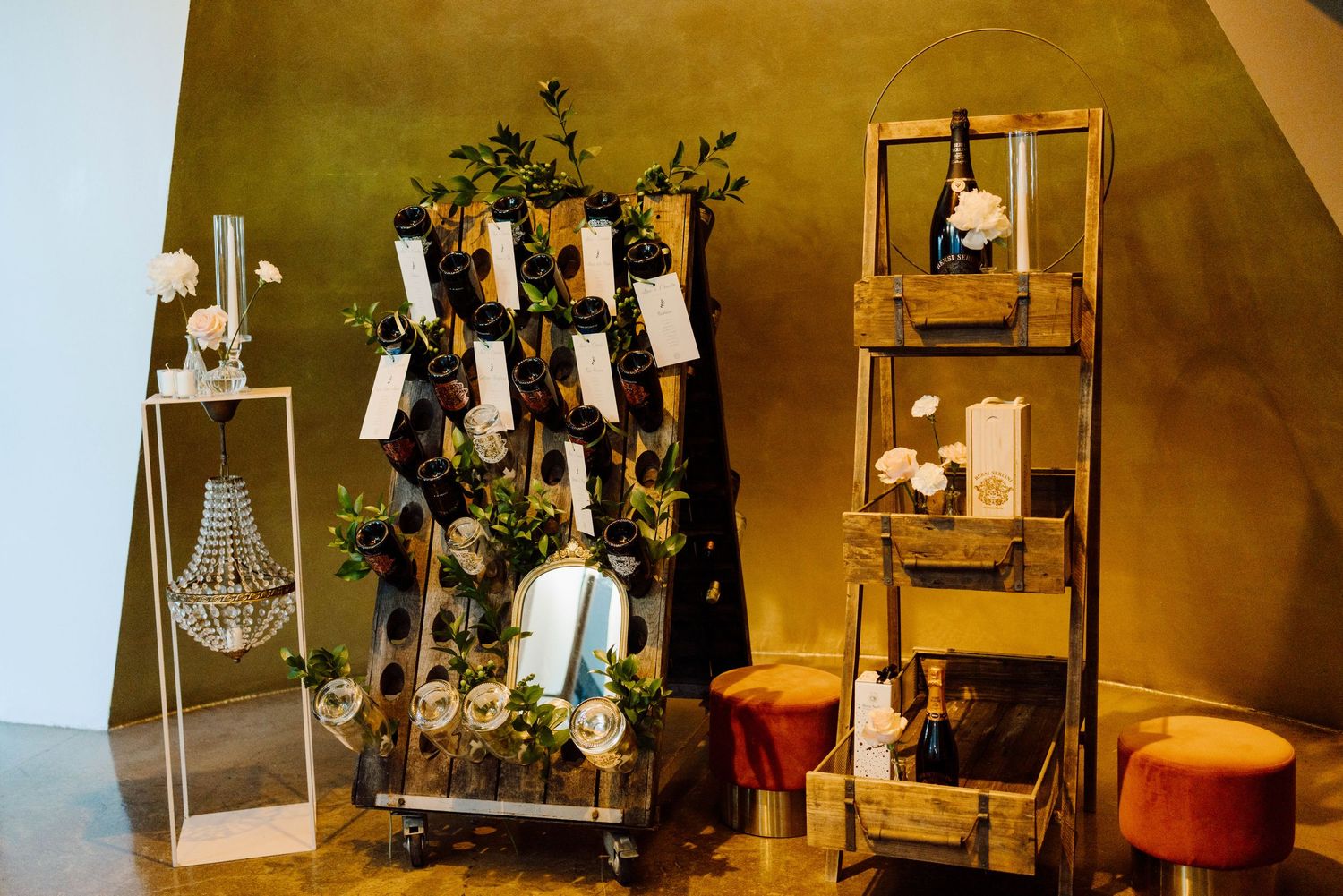 Rustic wedding seating chart display with wooden ladder, greenery, and floral arrangements at elegant venue.