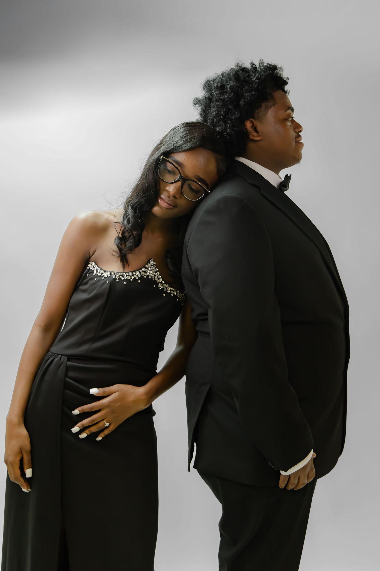Black and white maternity photo of couple in satin and leopard print dress, tenderly touching foreheads together.