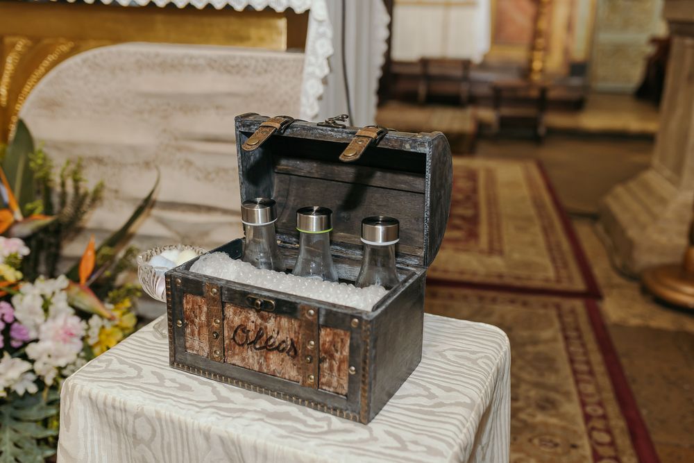 Vintage wooden treasure chest open on a table displaying glass bottles at a wedding ceremony.Jo Matos Fotografia Reportagem de Batismo