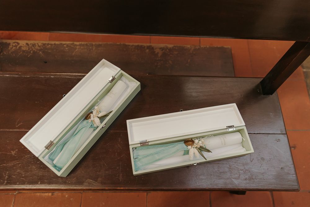 Two open white gift boxes with blue ribbon and dried flowers on a dark wooden table.Jo Matos Fotografia Reportagem de Batismo