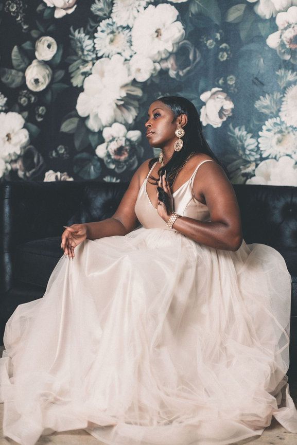 Elegant portrait against floral wallpaper wearing a flowing white formal gown.