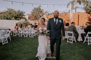 New husband and wife walking down aisle in front of their arch at their backyard wedding in San Diego CA after saying I DO