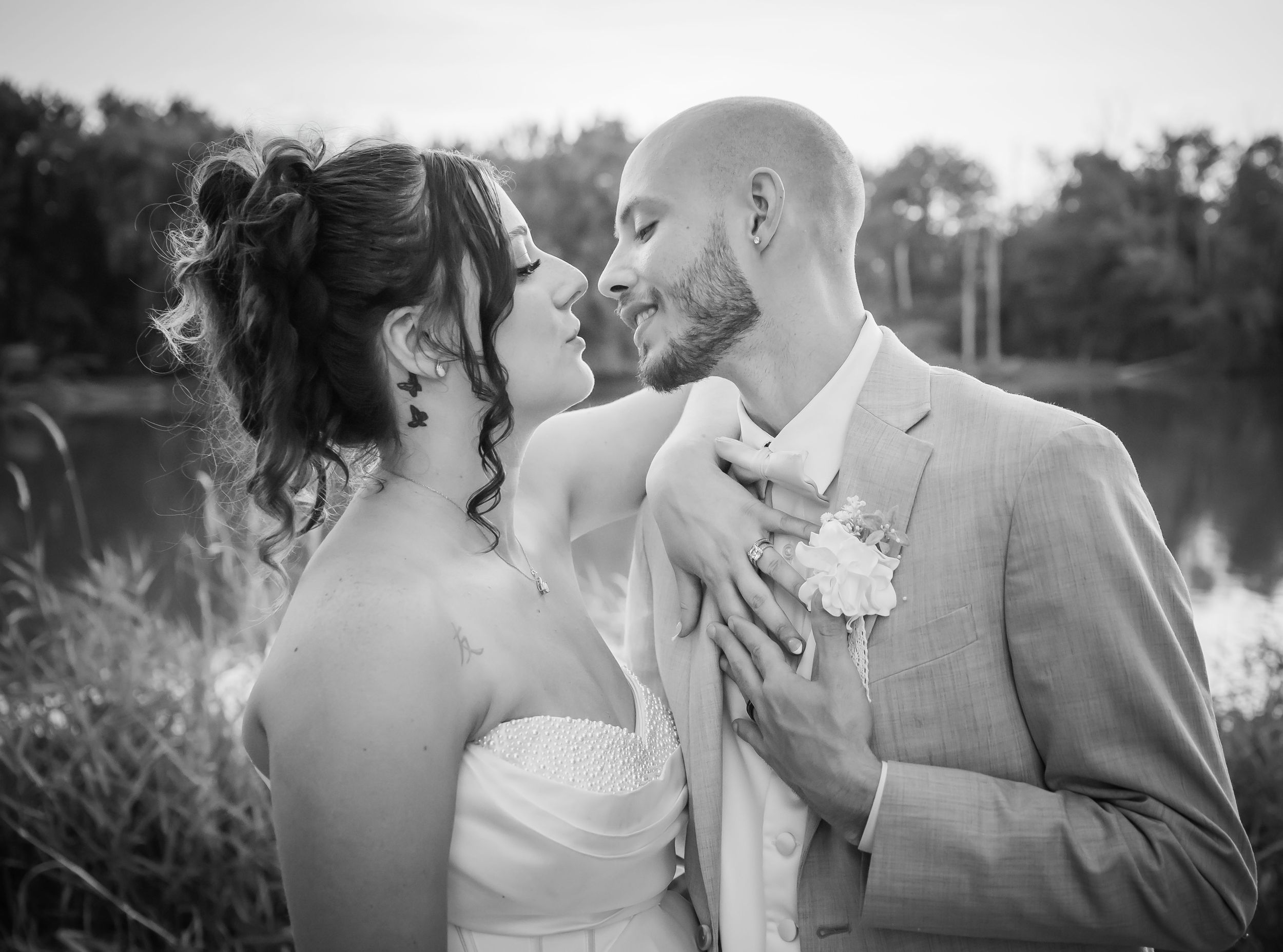 A tender black and white wedding moment with bride holding white bouquet as couple shares intimate kiss.