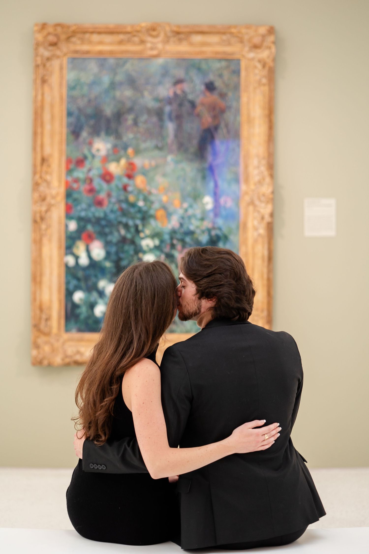 Couple sitting together viewing artwork in ornate gold frames at an art gallery.