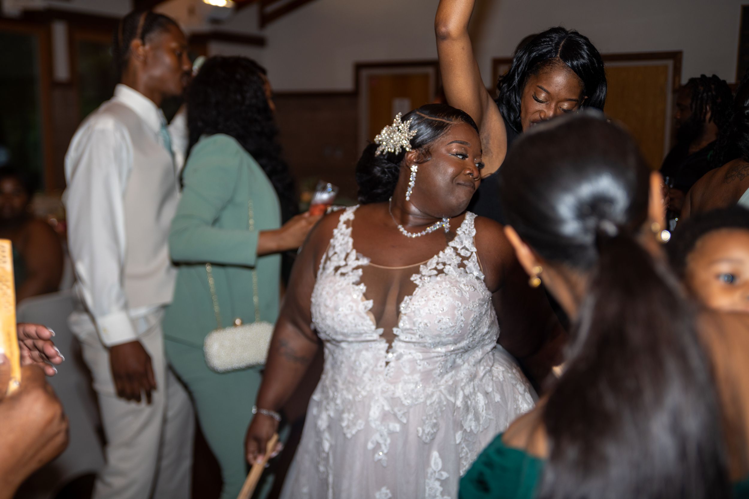Wedding celebration scene with bride in lace dress dancing at reception.