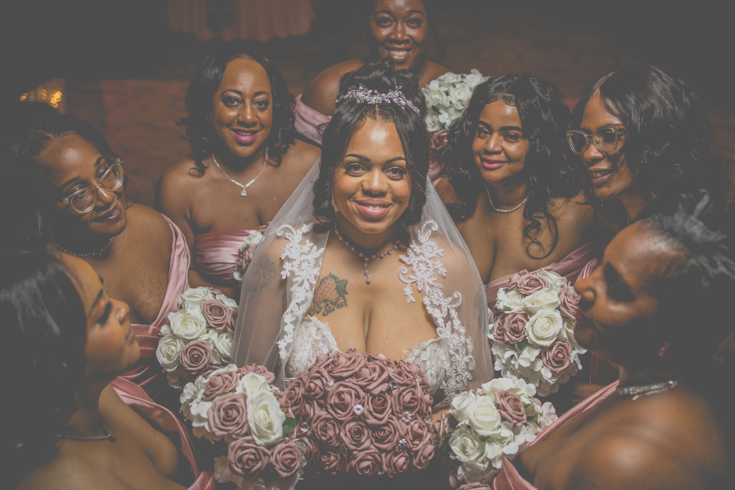 A group of bridesmaids in elegant mauve dresses share joyful moments with a bride in a traditional white wedding gown.