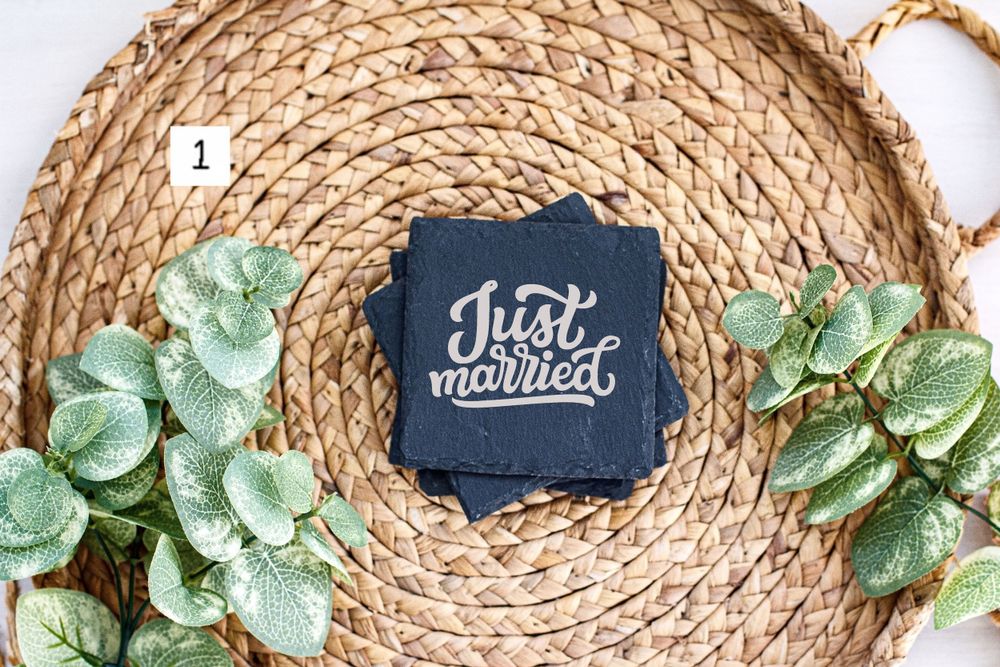 Wedding coaster with 'Just Married' text on dark blue background with decorative greenery and woven base.